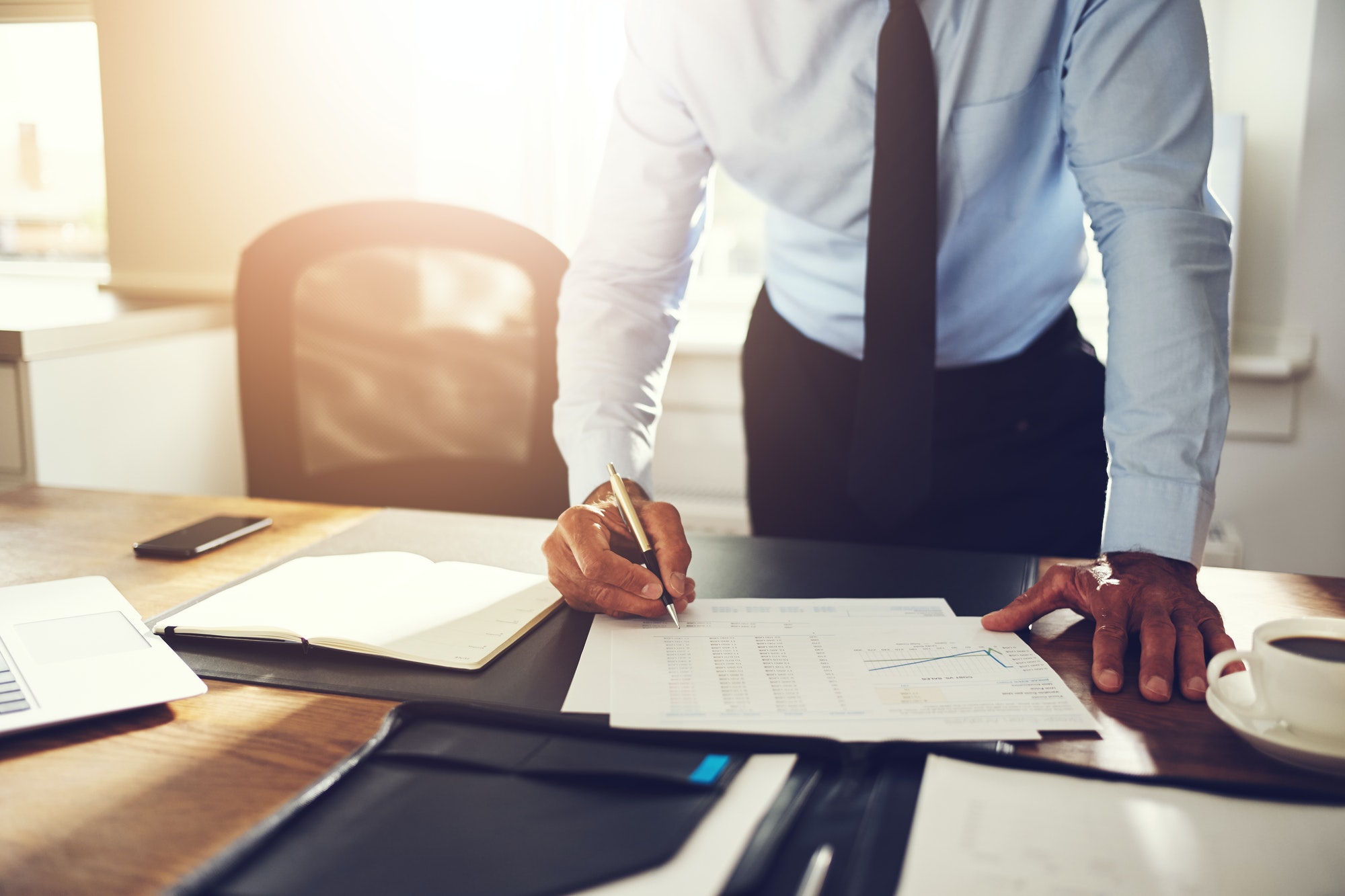 businessman-leaning-on-his-office-desk-signing-financial-documents.jpg